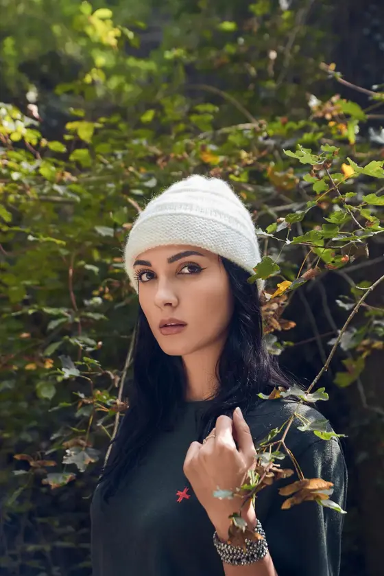 Model in a cream beanie among autumn leaves