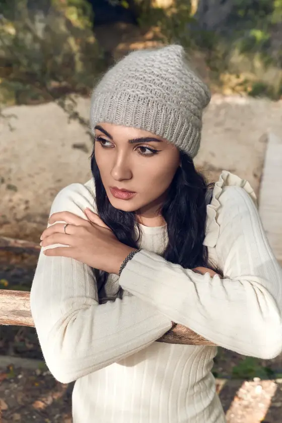 Model wearing a grey cable-knit beanie