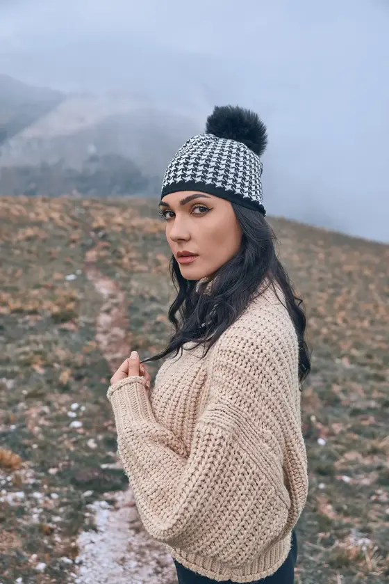 Model wearing a houndstooth beanie with a pompom