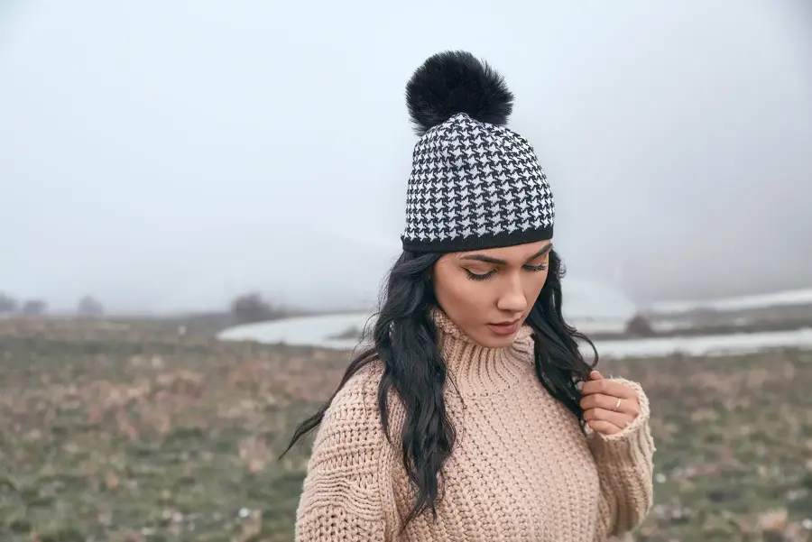 Model in a houndstooth beanie on a misty mountain